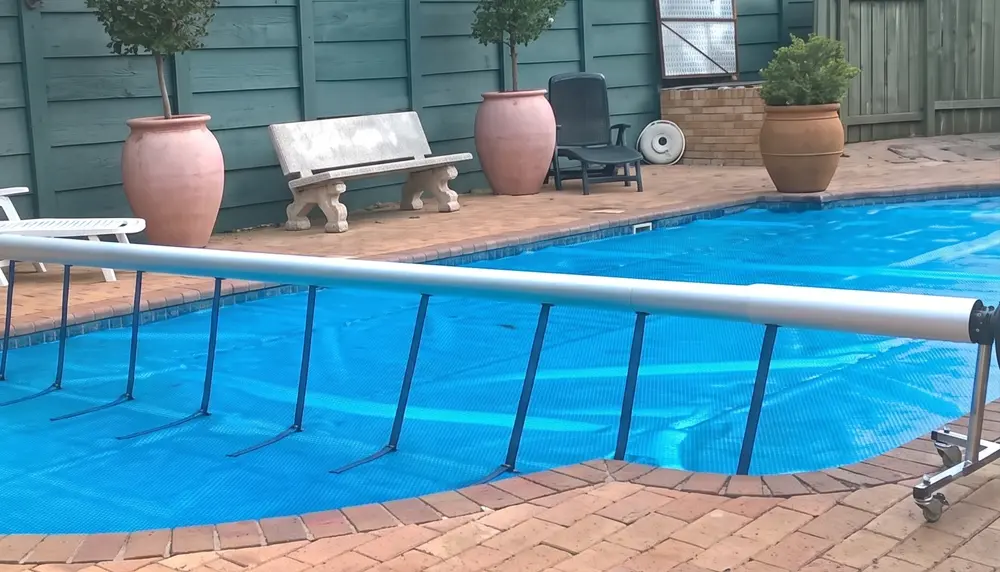 Pool cover roll-up station fitted to a solar pool cover